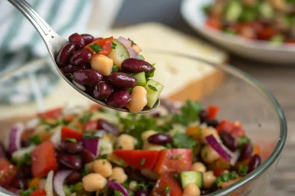 Close-up of a spoonful of dense bean salad with beans and vegetables