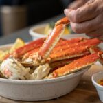 Close-up of snow crab legs being lifted, showcasing their texture and color.